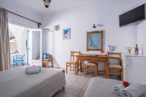 a bedroom with two beds and a desk and a table at Hotel Olympia in Karterados