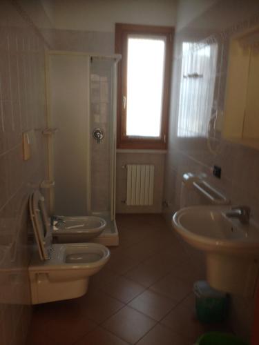 a bathroom with two sinks and a toilet and a window at Residence Vecchio Faro in Cavallino-Treporti
