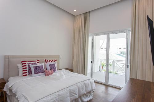 a white bedroom with a bed and a balcony at Las Villas Marina Pez Vela in Quepos