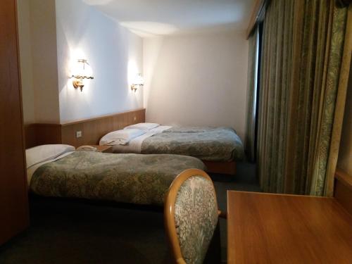 a hotel room with two beds and a table at Hotel Ottoz Meublé in Courmayeur