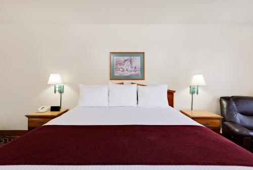 a hotel room with a bed and a chair at Days Inn by Wyndham San Angelo in San Angelo