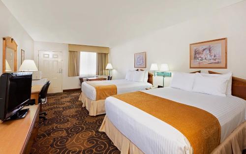 a hotel room with two beds and a flat screen tv at Days Inn by Wyndham San Angelo in San Angelo