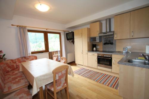 a kitchen with a table and a living room at Oberstockachhof in Schwendau