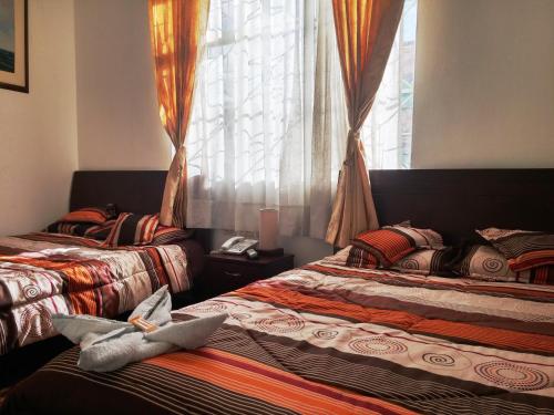 two beds in a room with a window at Hotel Andino Real in Bogotá
