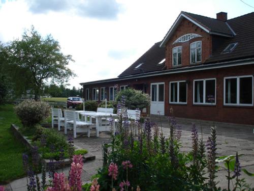 a house with white benches and flowers in front of it at Mikkelborg Kro in Rødding