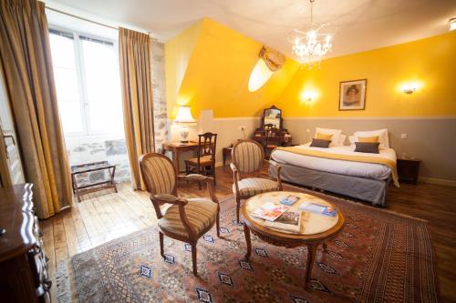 um quarto de hotel com uma cama, uma mesa e cadeiras em Château Hôtel Du Colombier em Saint Malo