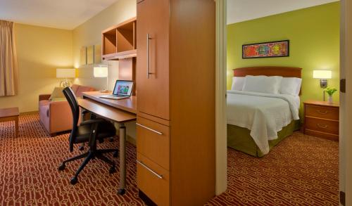 a hotel room with a bed and a desk with a laptop at Hawthorn Extended Stay by Wyndham Cincinnati NE Mason in Mason
