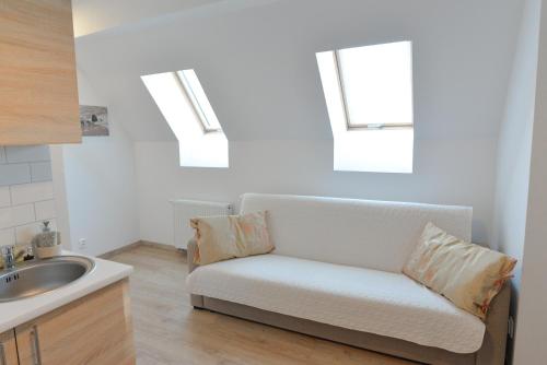 a white couch in a kitchen with two windows at Willa Muszelka - Apartamenty in Świnoujście