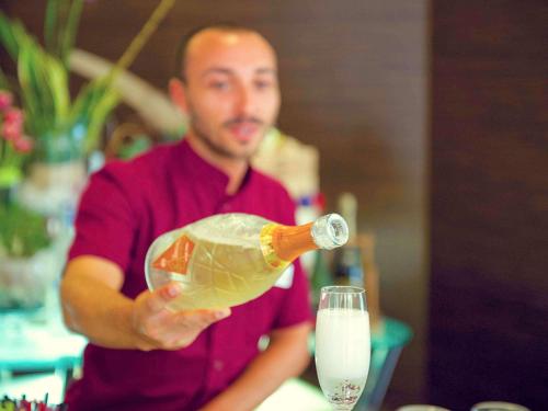 a man holding a bottle of champagne and a glass at Hotel Mercure Siracusa in Siracusa