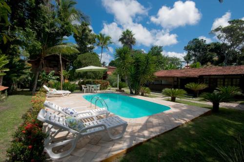 a pool with two lounge chairs and a table at Pousada Atlântida in Arraial d'Ajuda