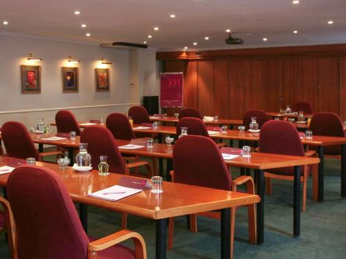 a conference room with wooden tables and red chairs at Mercure Hotel Bedfordview in Johannesburg