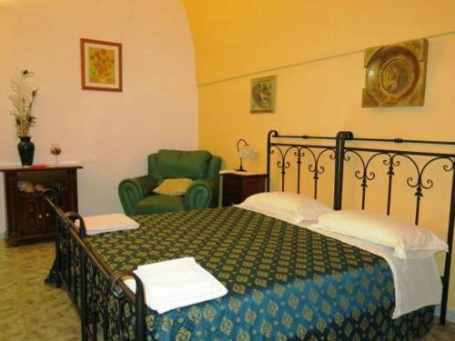 een slaapkamer met een bed en een groene stoel bij Oasi Rupestre in Montescaglioso