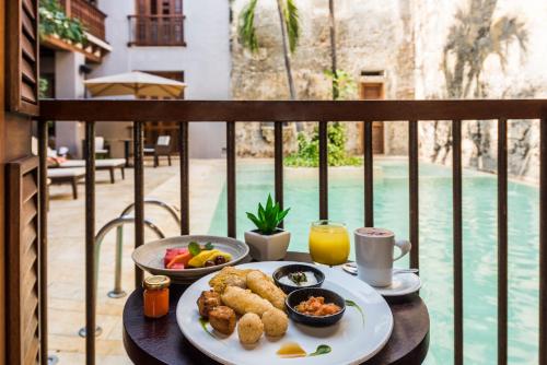 a table with a plate of food on a balcony at Ananda Hotel Boutique in Cartagena de Indias