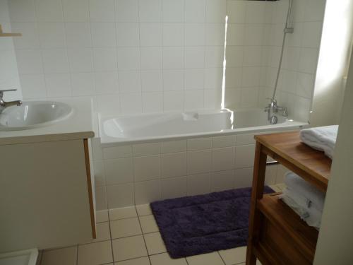 a white bathroom with a tub and a sink at Les Charmottes in Nuits-Saint-Georges