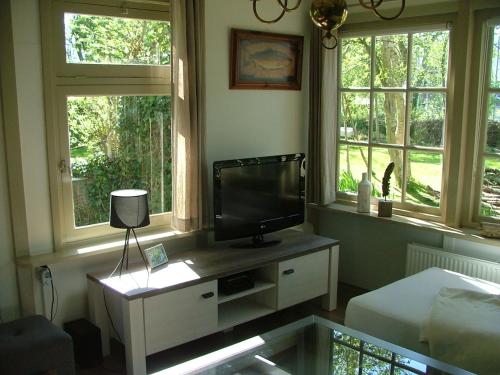 a living room with a tv and two windows at B&B Saense huisje in Assendelft