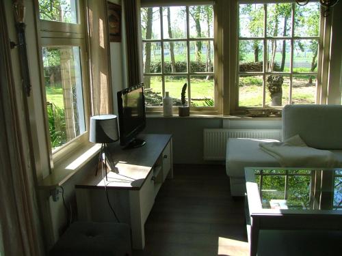 a living room with a couch and a tv and windows at B&B Saense huisje in Assendelft