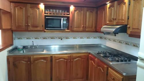 a kitchen with wooden cabinets and a sink and a microwave at Apartamento Rosita in Jardin