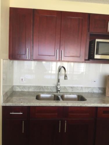 a kitchen with wooden cabinets and a sink at Waikiki Ala Moana Studio in Honolulu