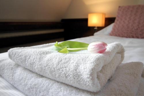 a towel with a flower sitting on top of a bed at Penzión Wellness & Restaurant Zoborská, free parking in Nitra