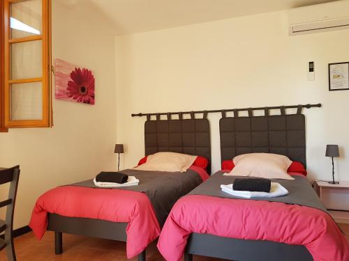 two beds in a bedroom with red and black sheets at A CASA DI L'ALIVU in Patrimonio