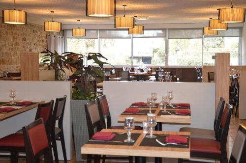 un restaurante con mesas y sillas de madera y ventanas en Hotel des Lauriers Roses, en Bourbonne-les-Bains
