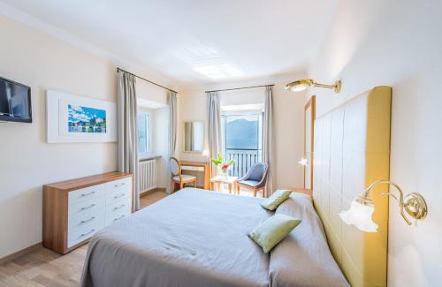 a bedroom with a bed and a desk and window at Villa Belvedere Como Lake Relais in Argegno