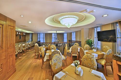 イスタンブールにあるAdelmar Hotel Istanbul Sisliのテーブルと椅子、薄型テレビ付きのレストランを提供しています。