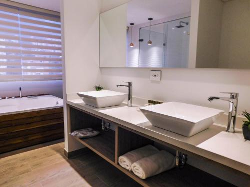 a bathroom with two sinks and a bath tub at Hotel Lomas 10 in Medellín