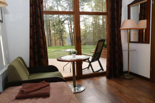 a room with a bed and a table and a window at Rezydencja Nad Wigrami Standard & Comfort Rooms in Gawrych Ruda