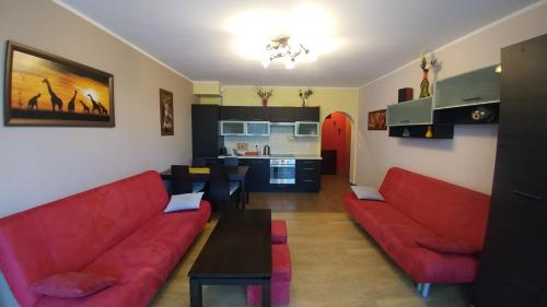レバルにあるApartament w Rezydencji Marino Rewalのリビングルーム(赤いソファ2台付)、キッチンが備わります。