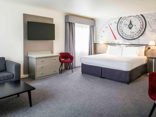 a hotel room with a bed and a clock on the wall at Mercure Dartford Brands Hatch Hotel & Spa in Ash