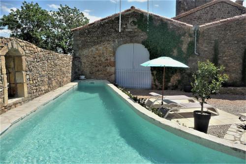 - une piscine avec un parasol à côté d'un bâtiment dans l'établissement Chateau Olmet, à Lodève