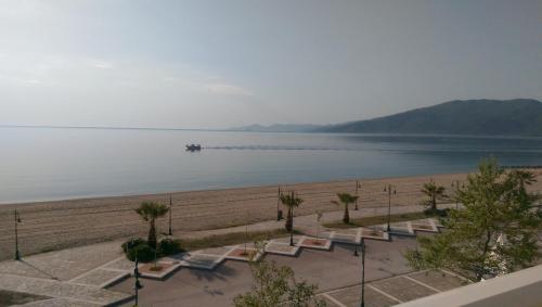 a row of chairs on a beach with a pier at Aimilias Family Apartments in Nea Vrasna