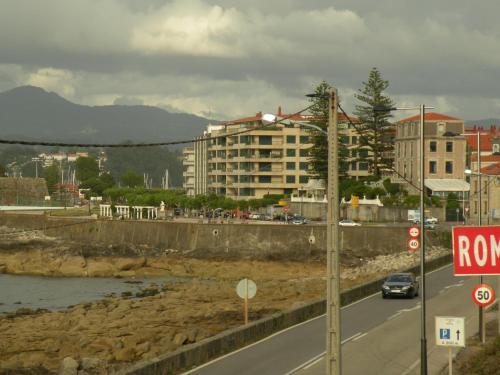 a car driving down a road next to a river at Hotel Rompeolas in Baiona