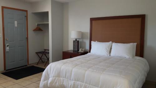 a bedroom with a large white bed and a door at Edgewater Inn in Sylvan Lake