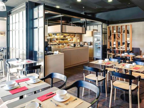 un restaurant avec des tables et des chaises et une cuisine dans l'établissement Mercure Périgueux Centre Historique, à Périgueux