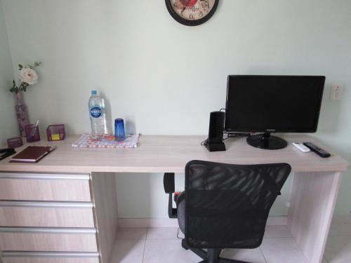 a desk with a computer monitor and a chair at Hospedagem Granville in São Paulo