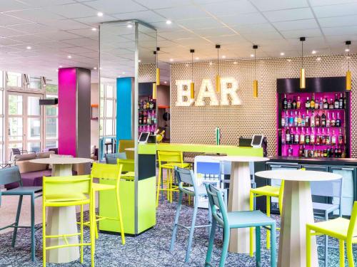 un bar avec des chaises et des tables colorées dans un restaurant dans l'établissement ibis Styles Antony Paris Sud, à Antony