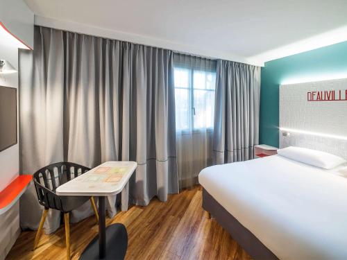 Zimmer mit einem großen weißen Bett und einem Stuhl in der Unterkunft ibis Styles Deauville Centre in Deauville
