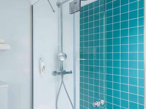 a bathroom with a shower with blue tiles at ibis Styles Deauville Centre in Deauville