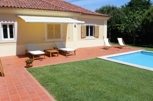 a backyard with a pool and chairs and a house at Dunas Golf House in Cascais