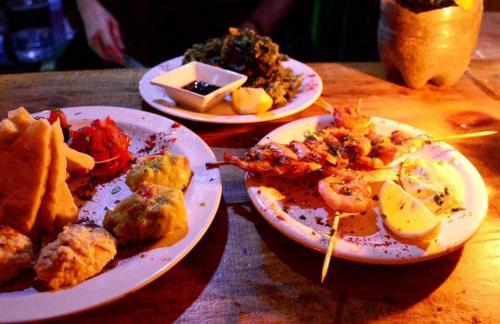 three plates of food on a wooden table at Lobo Hostel Bar in Cabo Polonio