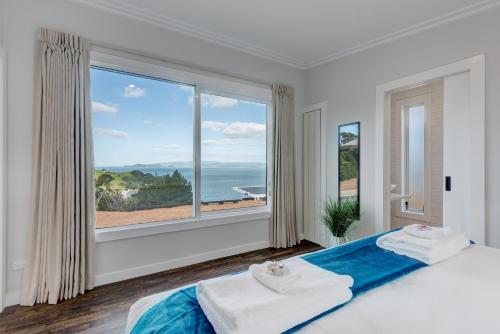 a bedroom with a large window with a view of the ocean at Woodside Bay Chalets in Ostend