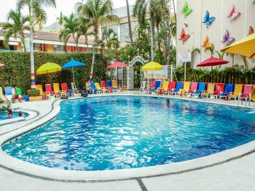 a swimming pool at a hotel with chairs and umbrellas at Sands Acapulco Hotel & Bungalows in Acapulco