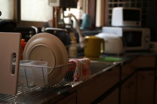 a kitchen counter with dishes in a strainer at Guest House Enishi in Toyama