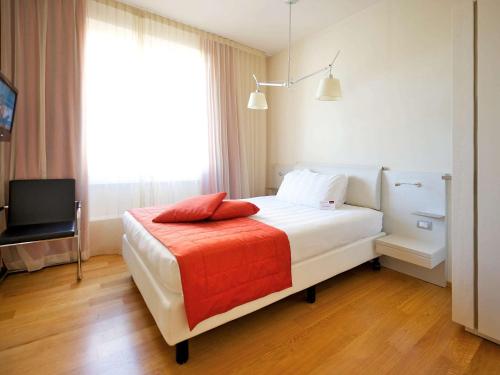 a bedroom with a white bed with a red blanket at Hotel Mercure Milano Solari in Milan