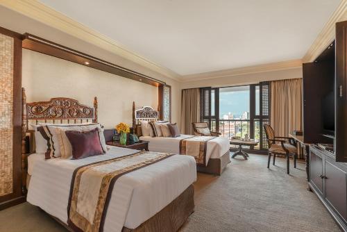 um quarto de hotel com duas camas e uma televisão em The Manila Hotel em Manila