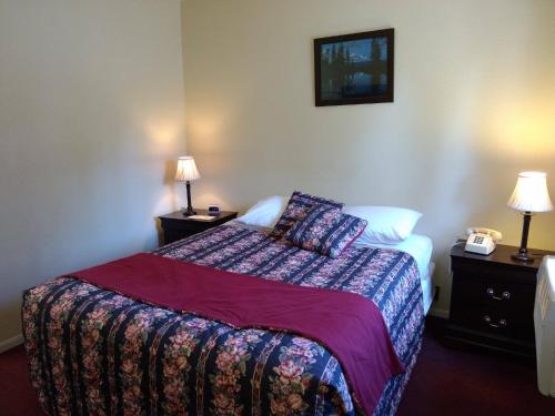 a bedroom with a bed and two lamps and a phone at Travelers Motel in Cottonwood