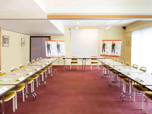 a room with rows of tables and chairs at ibis Styles Niort Poitou Charentes in Vouillé