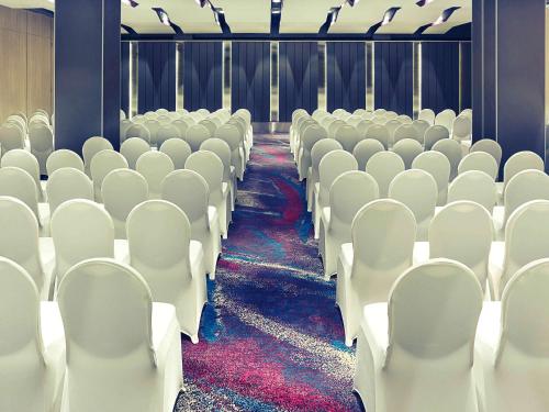 an empty auditorium with white chairs and a red carpet at Mercure Jakarta Sabang in Jakarta